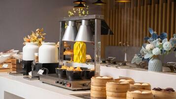 A buffet setup with various food items, including dumplings and a steam cooker.