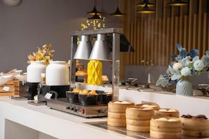 Un buffet con diversi piatti, tra cui gnocchi e una cuoci-vapore.