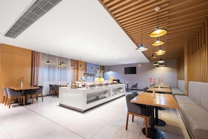 A modern dining area with a central buffet, multiple seating options, and pendant lighting.
