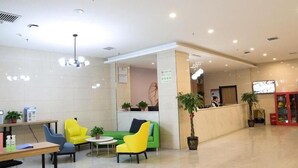 A hotel lobby with a reception desk, seating area with chairs, a small table, and potted plants. - Greentree Inn Xi an Baqiao District Hongqing Business Hotel (Xi'an)