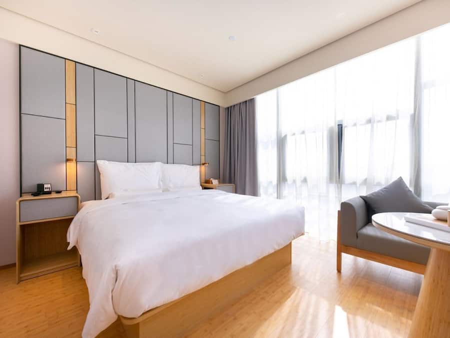 Ett modernt hotellrum med en stor säng, en sittgrupp med ett bord och utsikt genom stora fönster.