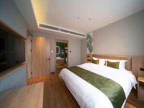 A modern hotel room with a large bed, wooden flooring, a television, and a bathroom visible through an open door. - Greentree Inn Express Hefei Yaohai Wanda Minghuang Road (Hefei)