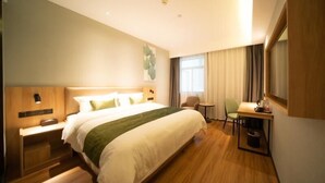 Een hotelkamer met een groot bed, een bureau, een stoel en een klein tafeltje.
