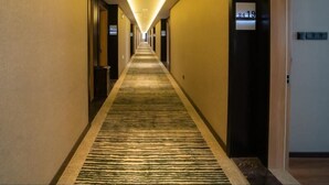 Een hotelgang met een vloerbedekking, deuren aan beide zijden en een bordje met daarop kamer 8419.