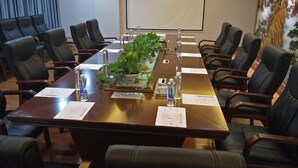 A conference room with a long table, chairs, a projector screen, and a floral wall mural.