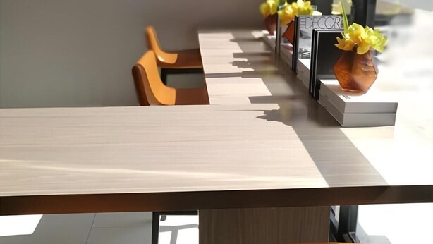 A modern interior with a long table, two chairs, and a vase with yellow flowers.