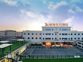A hotel with a modern design, featuring a central entrance, multiple floors, and a parking area.