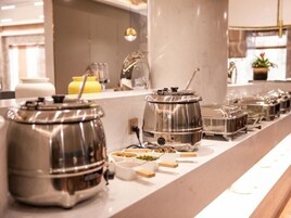 A buffet setup with various food containers and a coffee machine.