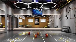 Ein modernes Fitnessstudio mit Trainingsgeräten, einem digitalen Bildschirm und einer Sitzgelegenheit.