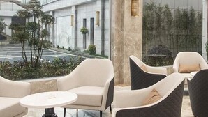 Ein stilvoller Lounge-Bereich mit Marmorboden, einem weißen Sofa und dunklen Sesseln.
