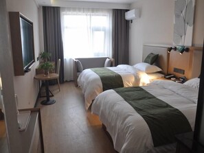 Une chambre d’hôtel avec deux lits, une télévision, une petite table avec une plante et une fenêtre avec des rideaux.