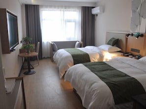 A hotel room with two beds, a small table with a chair, a potted plant, and a window with curtains. - Green Haotai Zhixuan Hotel (Shangqiu)