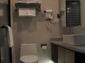 Une salle de bain moderne équipée de toilettes, d’un lavabo, d’un porte-serviettes et d’un sèche-cheveux.