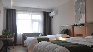 A hotel room with two beds, a desk with a chair, a potted plant, and a large window with curtains. - Green Haotai Zhixuan Hotel (Shangqiu)