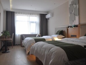 A hotel room with two beds, a desk with a chair, a potted plant, and a large window with curtains.