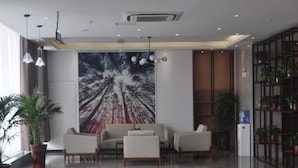 A modern lobby with a large forest-themed mural, a seating area with sofas and chairs, and a water dispenser.