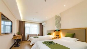 A hotel room with two beds, a desk, and a large window.