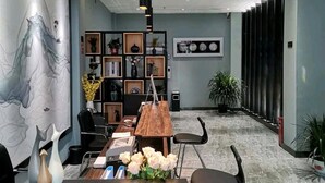 Een moderne vergaderruimte met een houten tafel, zwarte stoelen, een groot abstract schilderij, een boekenkast en een potplant.