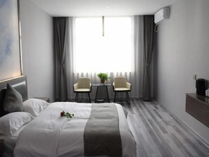 Ein Hotelzimmer mit einem Bett, zwei Stühlen, einem kleinen Tisch und einem Fenster mit Vorhängen.