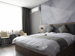 Une chambre d’hôtel moderne avec un grand lit, une table de chevet, une chaise et une fenêtre avec des rideaux.