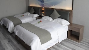 Een hotelkamer met twee bedden, een nachtkastje van hout en een groot abstract schilderij aan de muur.