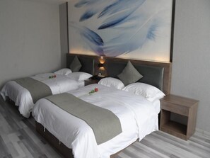 Une chambre d’hôtel avec deux lits, une table de chevet en bois et un grand tableau abstrait accroché au mur.