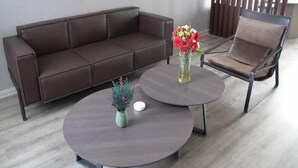 Un salon moderne avec un canapé en cuir marron, une table basse ronde ornée d’un vase de fleurs et un fauteuil marron.
