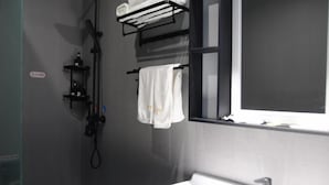 Een moderne badkamer met een douche, wastafel en raam.