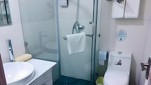 Un bany amb dutxa tancada amb vidre, un rentapeus blanc i un vàter.