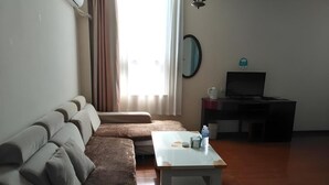 Un saló amb un sofà, una taula de centre, una televisió i una finestra amb cortines.