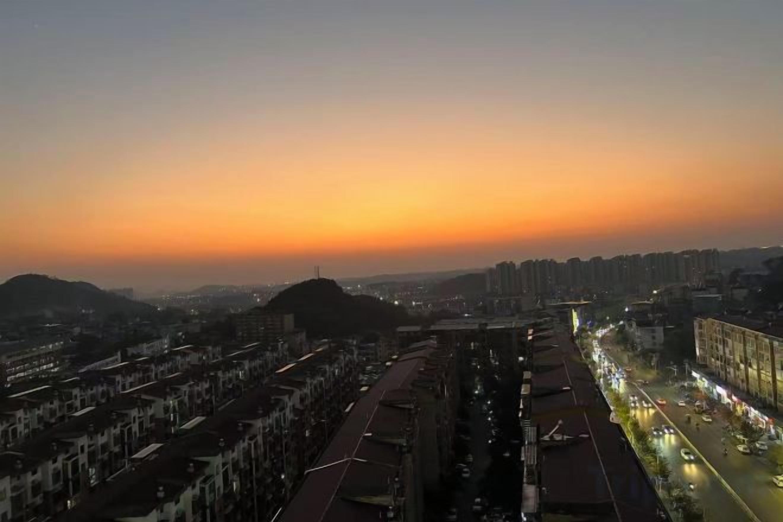 Ein Stadtbild im Abenddämmerung mit Sonnenuntergang, Straßen und Gebäuden.