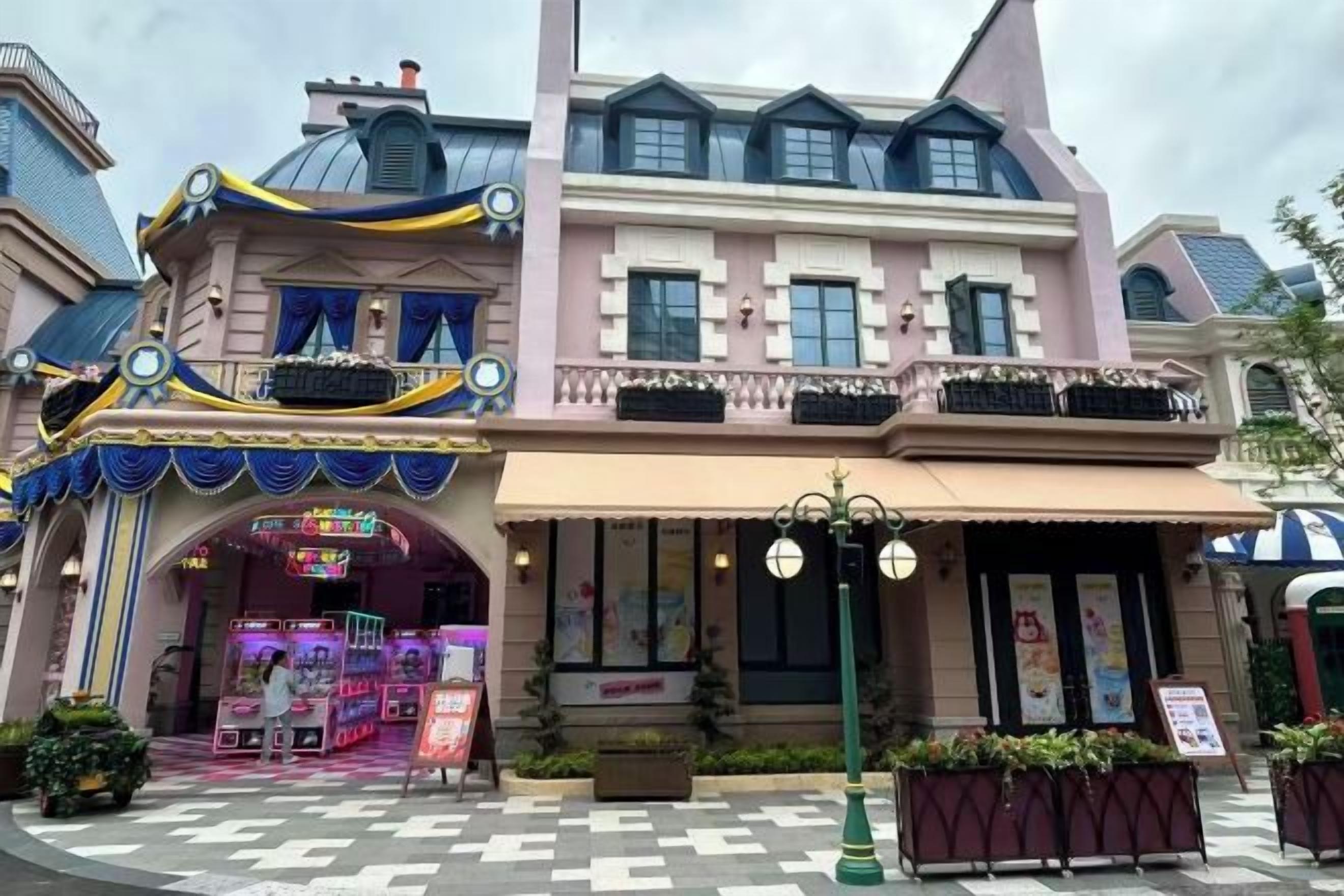 A building with a pink facade, a balcony with black railings, and a storefront with a sign.
