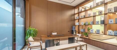 Interior moderno com balcão de atendimento em madeira, área de estar e prateleiras de exposição.