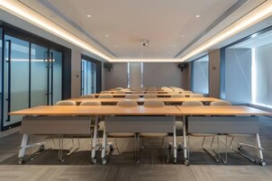 Un salón de conferencias con una larga mesa, sillas y un proyector.