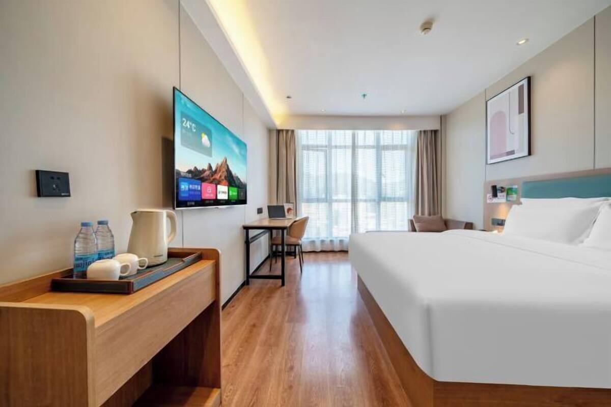A modern hotel room with a bed, desk, and TV.