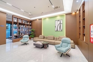 Un vestíbulo moderno con un sofá, sillones, una mesa de centro y una estantería.