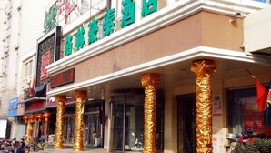 Fachada de hotel com placa indicando ser hotel, colunas revestidas com material dourado e visão clara da entrada.