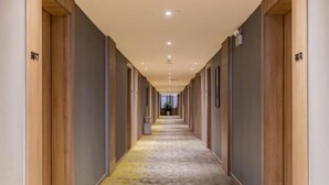 A long, narrow hotel corridor with wooden doors on both sides, numbered room signs, and a patterned carpet. - Greentree Eastern Bengbu Huaishang District Wanda Plaza Haijixing Hotel (Bengbu)