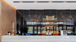 A modern hotel lobby with a traditional Asian architectural design, a reception desk, and a self-service kiosk. - Greentree Eastern Bengbu Huaishang District Wanda Plaza Haijixing Hotel (Bengbu)