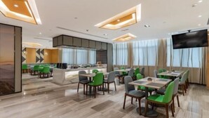 A modern dining area with a central island, green and grey chairs, and a flat-screen TV mounted on the wall. - Greentree Eastern Bengbu Huaishang District Wanda Plaza Haijixing Hotel (Bengbu)