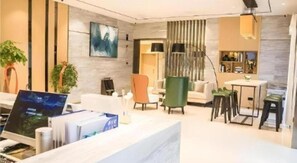 Un moderno vestíbulo de hotel con recepción, zona de estar y comedor.
