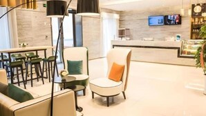 En moderne hotellobby med siddeplads, en receptionsdisk og et fjernsyn.