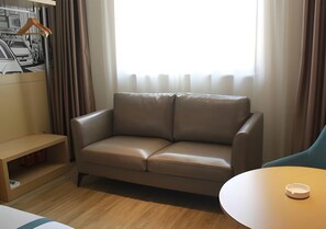 Una habitación con un sofá de cuero marrón, una mesa de madera y una estantería de madera.