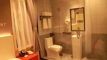 Un baño moderno con cabina de ducha de vidrio, inodoro y tocador con espejo.