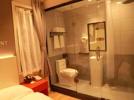 Un baño moderno con cabina de ducha de vidrio, inodoro y tocador con espejo.