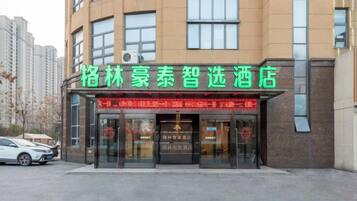 A hotel with a prominent green signboard, large windows, and a visible entrance.