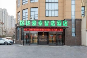 Een hotel met een opvallend groen bord, grote ramen en een duidelijke ingang.