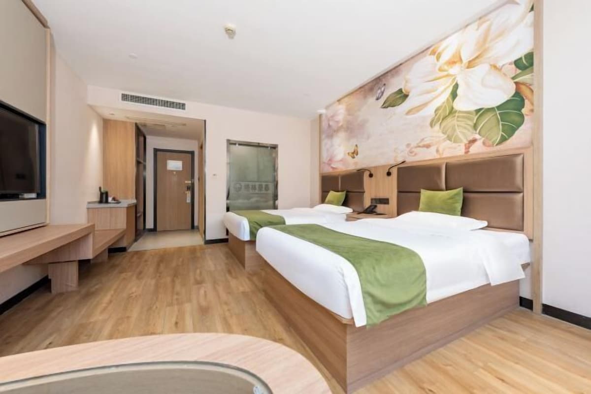 Et hotelværelse med en stor seng, et skrivebord og et fjernsyn.