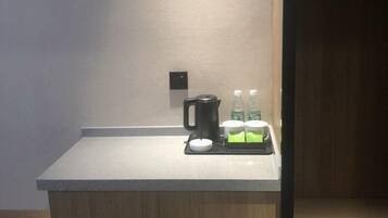 Une petite cuisine équipée d’une machine à café, d’une bouilloire et de sachets de thé, le tout posé sur un plan de travail.