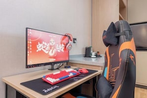 En computeropsætning med skærm, tastatur og hovedtelefoner på et skrivebord.